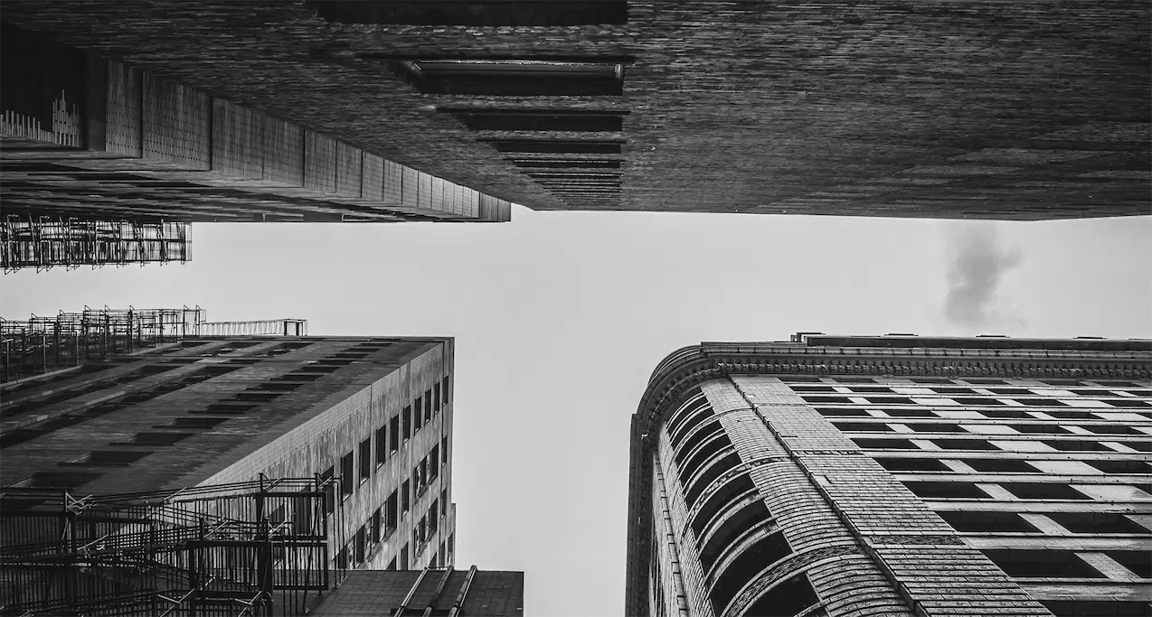 Klassiske højhuse i mursten set nedefra mod himlen – illustration af et holdingselskab