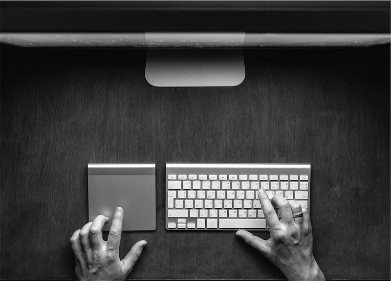 Hænder skriver på tastatur foran computerskærm, mens bestillingen udfyldes online